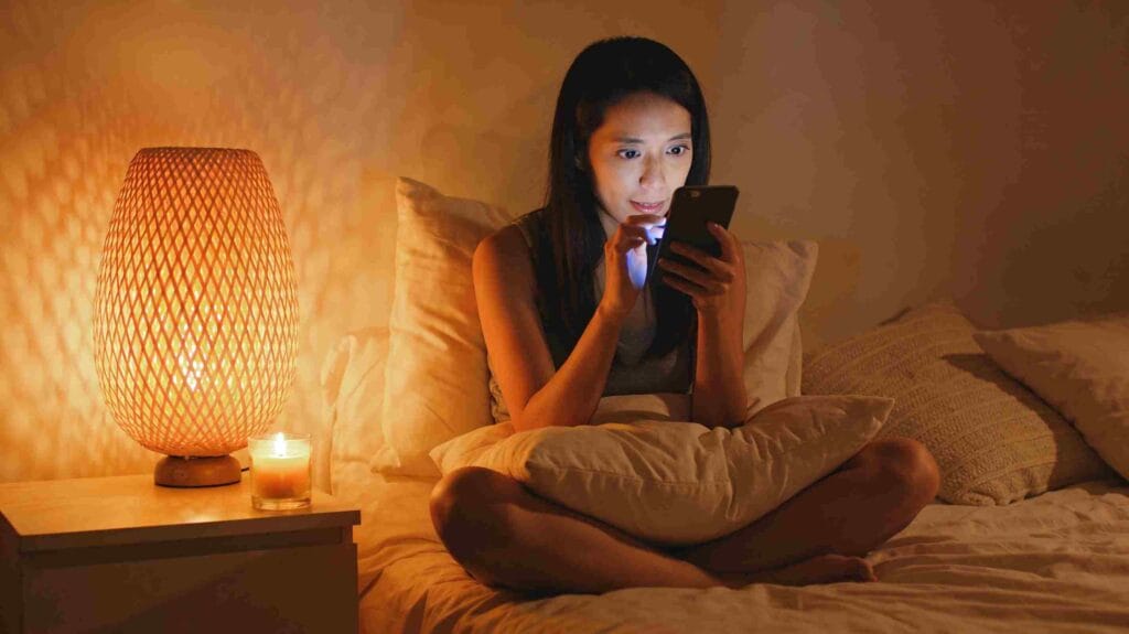 Woman reading an online love psychic chat on her phone in bed at night