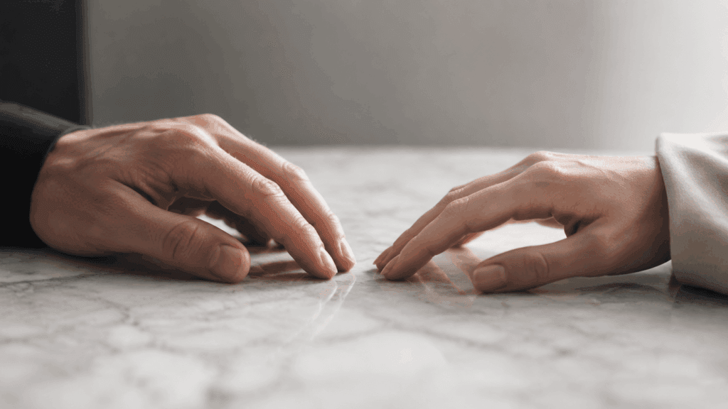 Two hands almost touching on a marble table but not quite making contact, symbolizing the emotional distance of a Libra man hot and cold